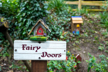 Fairy Doors wooden sign post with fairy houses in charming outdoor fairy garden in Ireland.