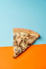 Slice of pizza with chicken fillet, mushrooms, spinach, mozzarella and gouda cheeses with creamy sauce. Blue orange background. view from above. copy space
