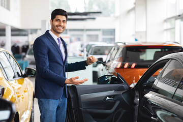 Cheerful middle eastern sales manager showing nice car
