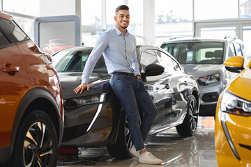Confident arab guy businessman buying new car at dealership salon
