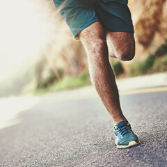 Time for these feet to burn up the pavement. Low angle shot of a mans legs running along a road.