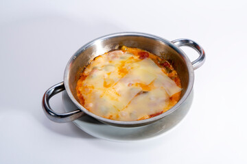 View of Turkish traditional food menemen with cheddar cheese, from opposite or side view, with selective focus on isolated setting, gray background.