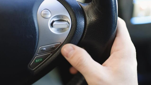 Driver sets up the cruise control of an autonomous car while driving down the scenic road in the countryside. Steering wheel button the adaptive Cruise Control while driving a car