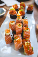 Close up of gourmet sushi rolls with salmon, masago (fish eggs), avocado, octopus and nori in a white plate