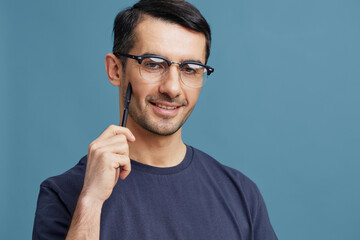 portrait man in blue t-shirts with a pen in hand posing emotions blue background