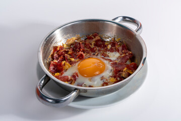 Close-up view of eggs with bacon in isolated setting, gray background with selective focus, from opposite or side angle.