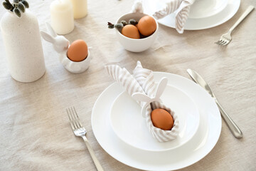 Rabbit Easter egg in napkin on plate. Easter dinner table setting concept.