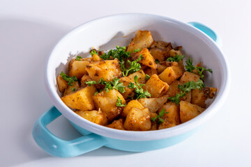 Cropped view of square sliced potato dish in pan, shot with selective focus from counter angle on white background in isolated setting.