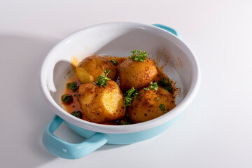 Cropped view of potato dish in pan, shot with selective focus from counter angle on white background in isolated setting.