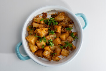 Cropped view of square sliced potato dish in pan, shot with selective focus from overhead angle on white background in isolated setting.