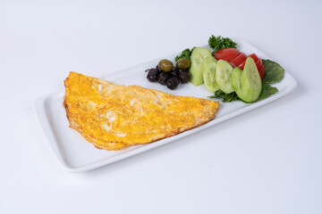 Cropped view of cucumber and tomato slices, olives and classic double-wrapped omelet on white plate, shot with selective focus on white background in isolated setting.