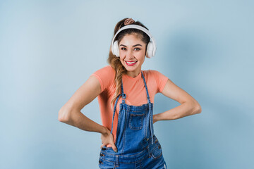 hispanic young woman with headphones, dancing and listening music on blue background in Mexico Latin America