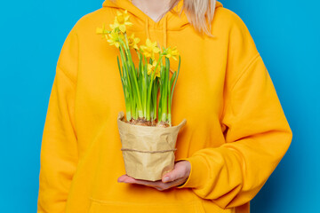 Stylish female in yellow hoodie with daffodil flowers