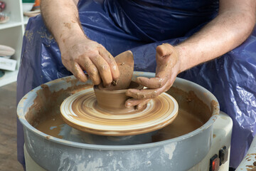 senior pottery man hands sculping from clay on pottery wheel pot in workshop. Concept of ceramic hobby art