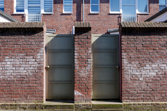 Outdoor front street view of two steel entrance door and brick wall fence of two townhouse. 