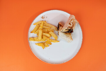Cropped view of potatoes and round meatball wrap shot with selective focus from overhead angle on isolated orange background.