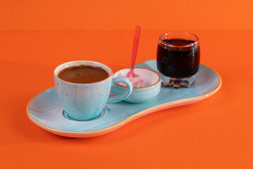 Image of traditional Turkish Coffee, Turkish delight and Turkish Cherry Sherbet Drink shot from opposite angle on isolated orange background.