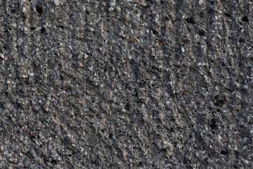 Texture of a decorative concrete wall. Rough gray surface with a grainy pattern of small stones and dents. Perfect for background and design. Closeup.