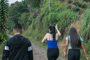 three latin boys hiking on an ecological trail in Colombia while documenting nature with their cell...