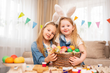 a happy little girls with rabbit ears hold basket with painted eggs