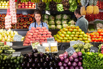 Posing adult woman and working man in fruit and vegetable shop