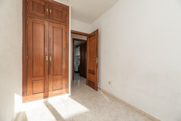Empty room with light stoneware floor, two-body built-in wardrobe with trunk and door of the same color