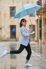 Woman jumping over a puddle on a rainy day