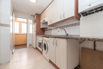 Kitchen with furniture and drawers in light tones with details in wood and pink granite countertops with white appliances and a washing machine and porcelain stoneware floors