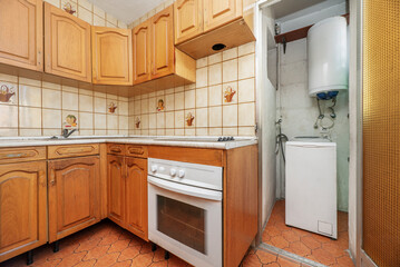 Kitchen with Castilian-style furniture in gloss varnished pine wood, similar pink granite countertop and vintage kitsch floors, washing machine and white oven