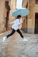 Woman jumping over a puddle on a rainy day