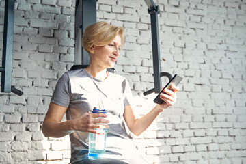 Sporty woman using smartphone in fitness center