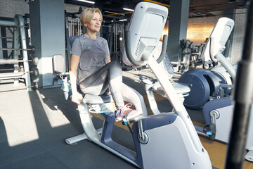 Cheerful woman using fitness equipment in gym
