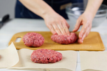 Woman's hand forming a beef meat for a hamburger party. Portioning ground meat. Homemade burgers....