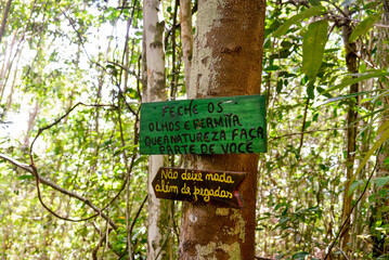 tree sign in the forest with the phrases: "Close your eyes and allow nature to be a part of you" and "Leave nothing but footprints", signposted trail