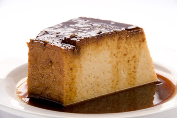 Neapolitan flan on a white background, slice of pudding dessert with caramel sauce, close up view