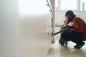 African American male watching the baking of biscuit with his daughter