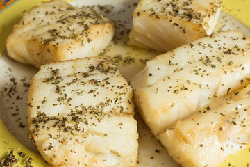 Close-up of species on cooked cod loins on a decorative plate.