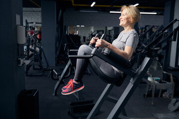 Fototapeta na wymiar Joyful woman using fitness equipment in gym