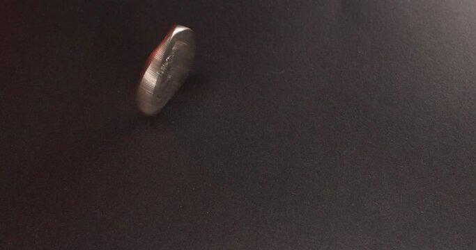 One Dollar coin, Eisenhower Dollar spinning on dark surface. Rotating, one Dollar coin.