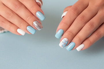 Beautiful female hands with romantic manicure nails, blue and white gel polish