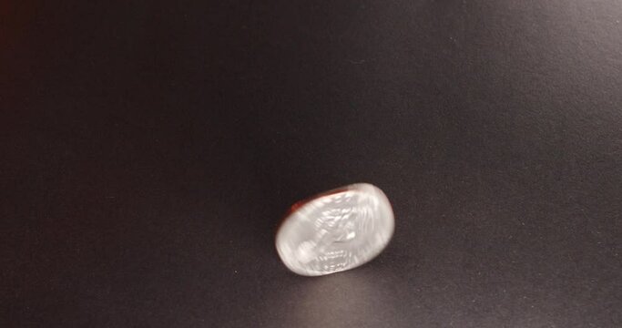 One Dollar coin, Eisenhower Dollar spinning on dark surface. Rotating, one Dollar coin