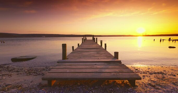 Sea sunset or sunrise and wooden old jetty pier for fishermen, calm nature landscape. Travel