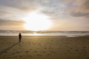 Adventurous athletic woman walking on Pacific Northwest beach during a beautiful sunset.