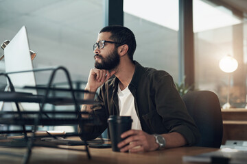Focus and consistency keeps you on task. Shot of a young businessman using a computer during a late night in a modern office.