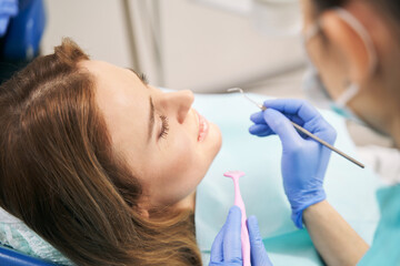 Doctor hands examining woman teeth with dental tools