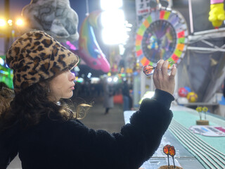 Profile of a woman in hat throwing a dart in a fair