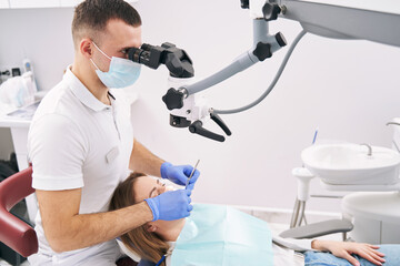 Dentist examining woman teeth with microscope in dental clinic