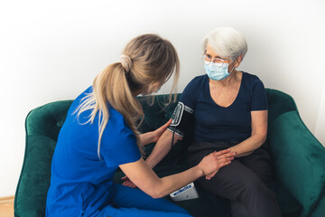 Elderly person looses her strength and has her blood pressure monitored by professional nurse. High...