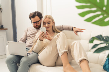 Young Caucasian couple working on the sofa with gadgets remote job . High quality photo