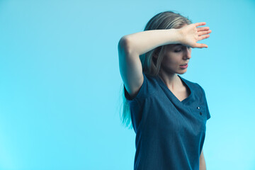 Devastated and stressed caucasian female nurse touching her forehead with her palm. Blue background. Studio shot. High quality photo